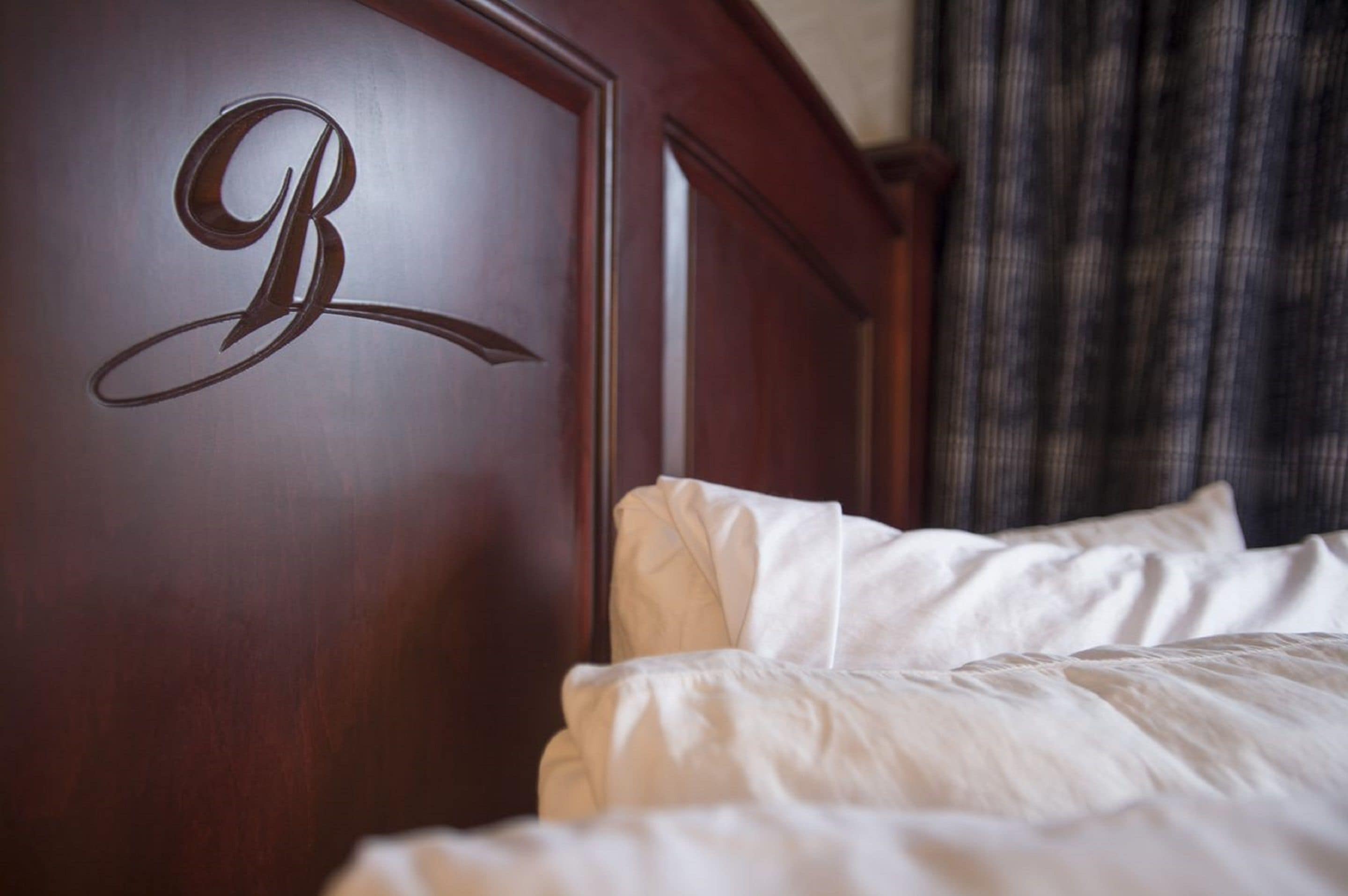 Une tête de lit en bois ornée d’un monogramme avec la lettre « B ».