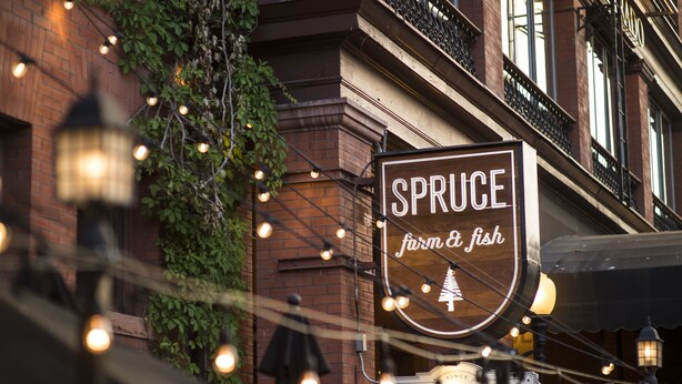 A sign for 'SPRUCE farm & fish' with a 'LIQUOR BAR' sign below it, surrounded by string lights. - Hotel Boulderado (Boulder)
