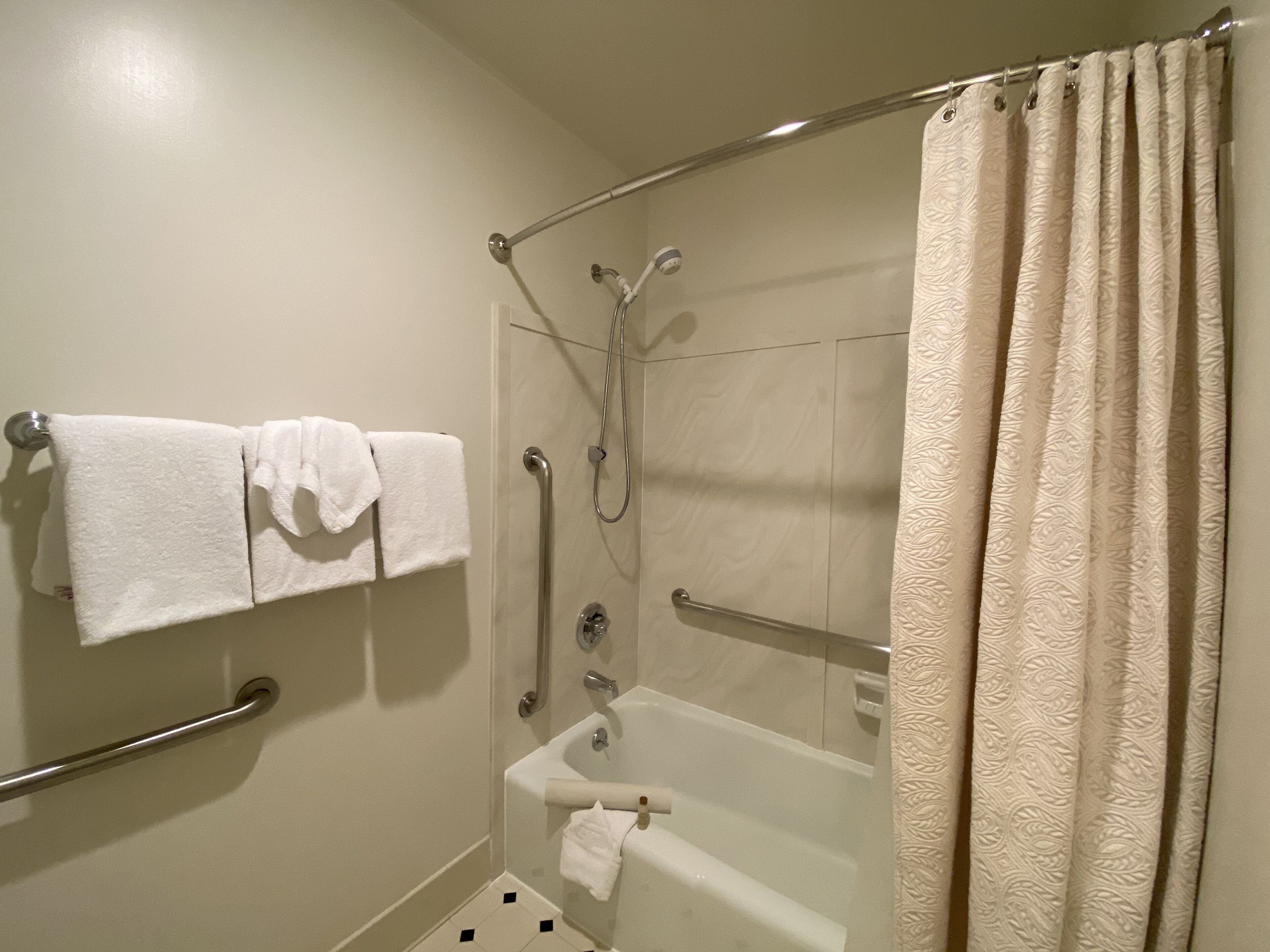 Une salle de bain avec une baignoire, une douche et des toilettes. Deux serviettes sont suspendues sur un porte-serviettes.