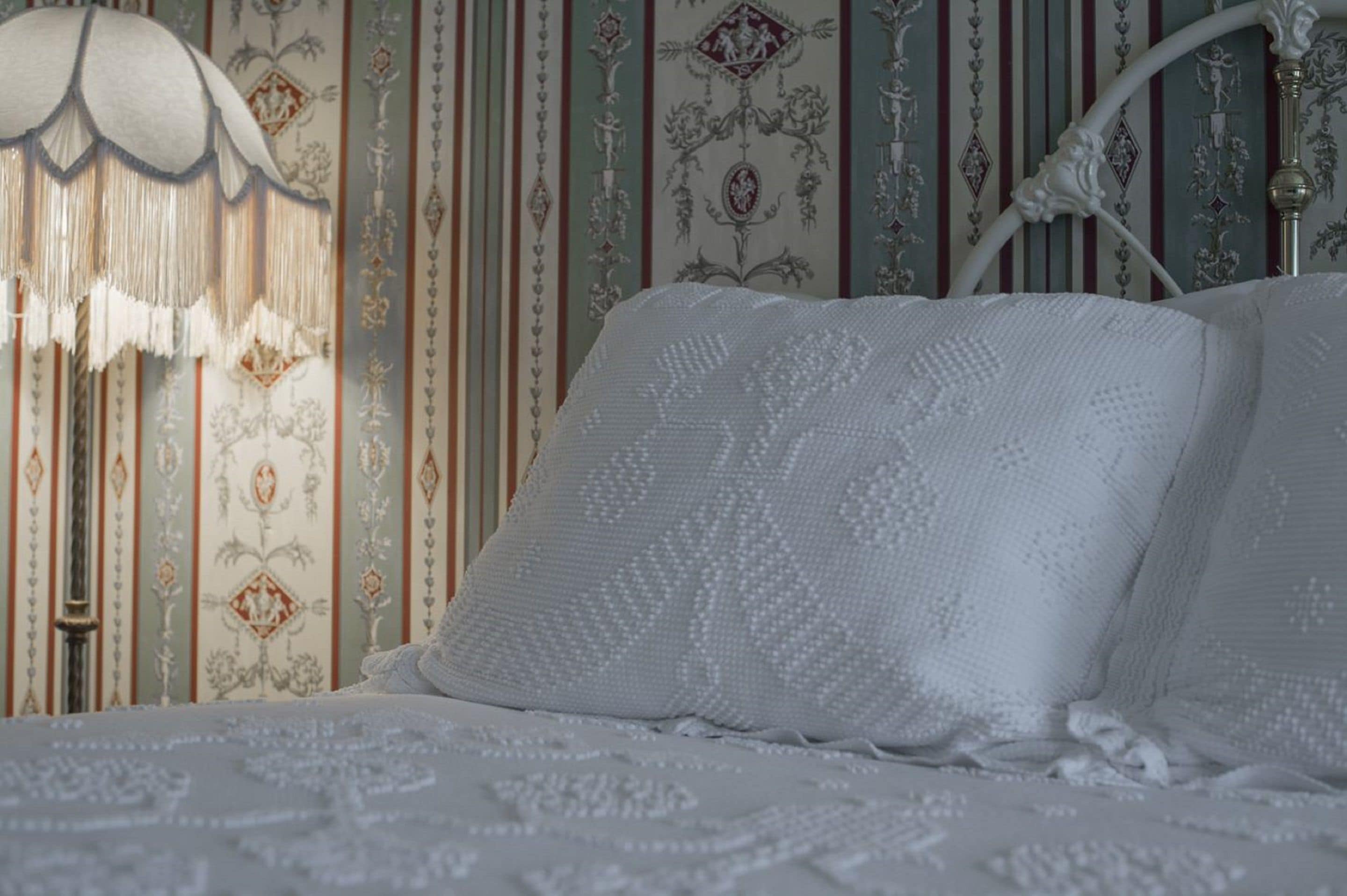 Una cama con ropa blanca y un cabecero decorativo.