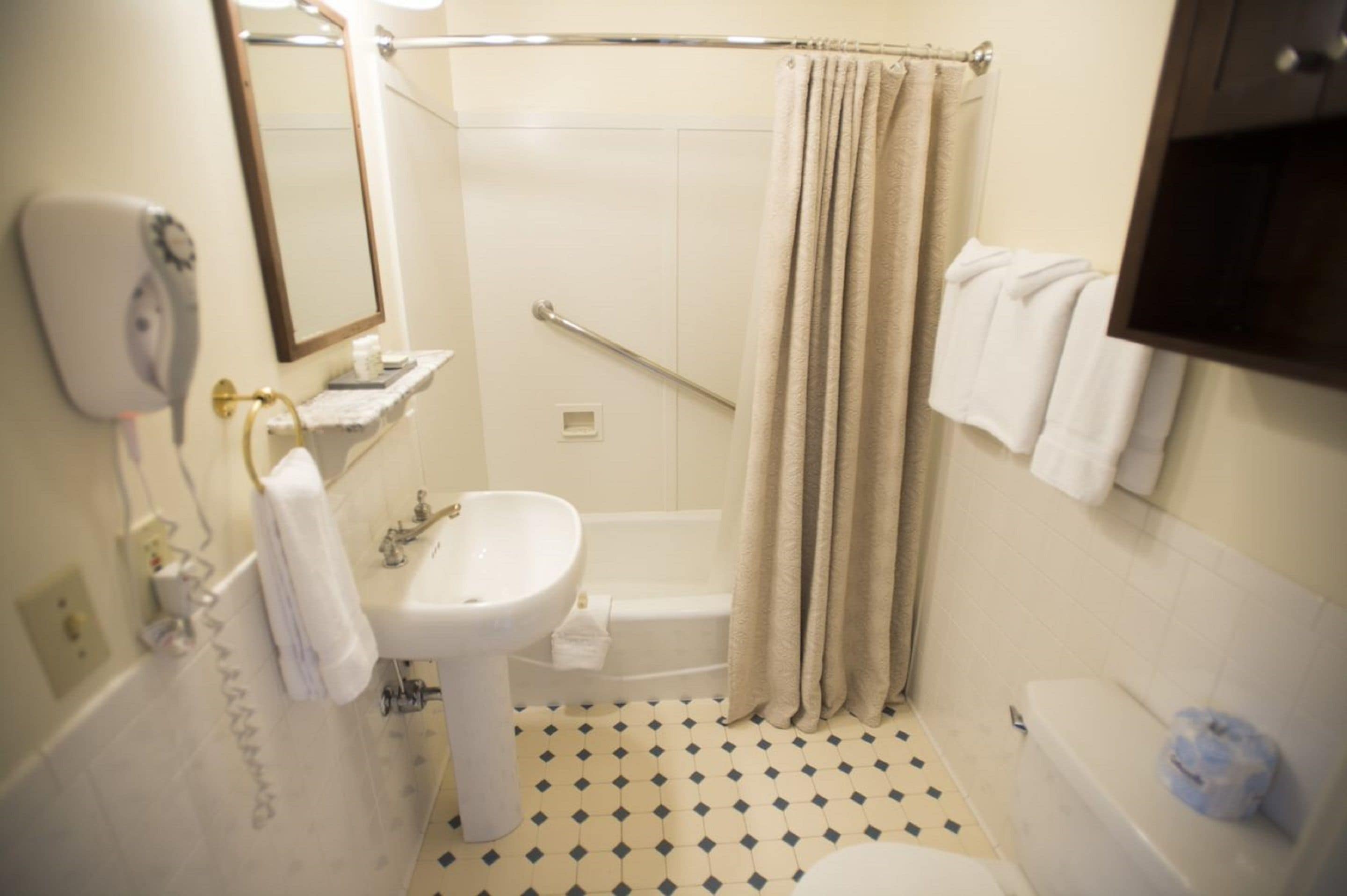 Un baño con lavabo, espejo, toallero, cortina de ducha y bañera.