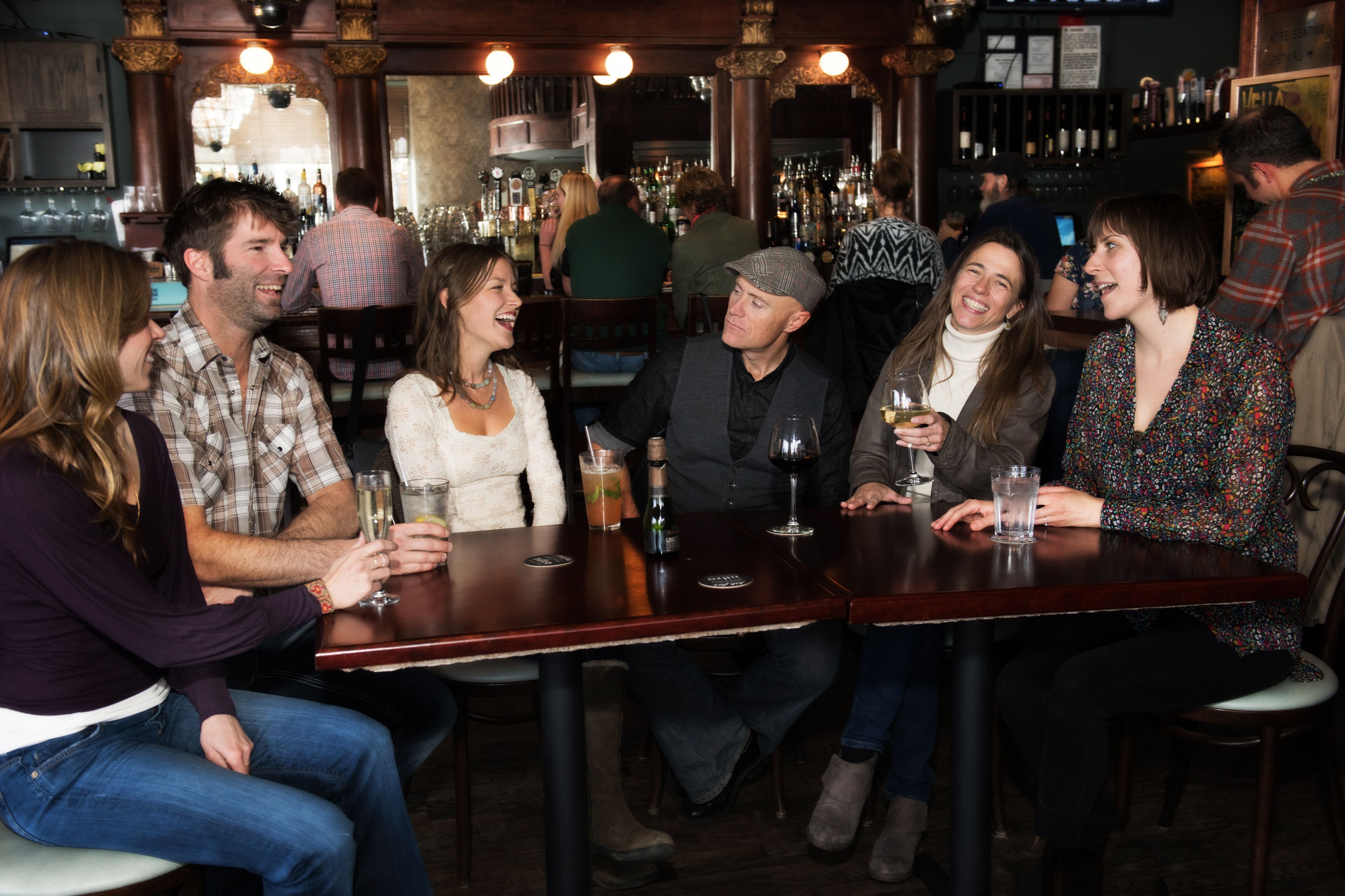 A group of people seated at a bar with bottles and glasses on the counter.