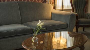 Een woonkamer met een grijze bank, een glazen salontafel en een vaas met bloemen.