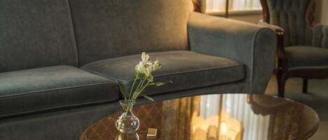 A living room with a grey sofa, a glass coffee table, and a vase with flowers.