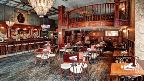 A spacious bar area with wooden furniture and a chandelier. There is a second-floor balcony with a railing. - Hotel Boulderado (Boulder)