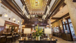 A grand lobby with a high ceiling, ornate wooden railings, and a central chandelier. - Hotel Boulderado (Boulder)