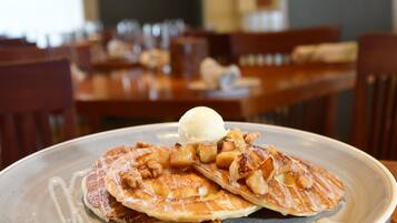 A plate of pancakes with apple slices and a scoop of ice cream on a ceramic plate.