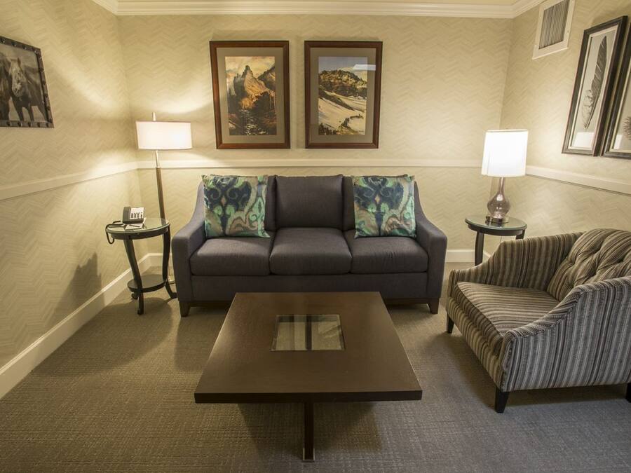 Una sala de estar con un sofá, un sillón a rayas, una mesa de centro y dos lámparas.