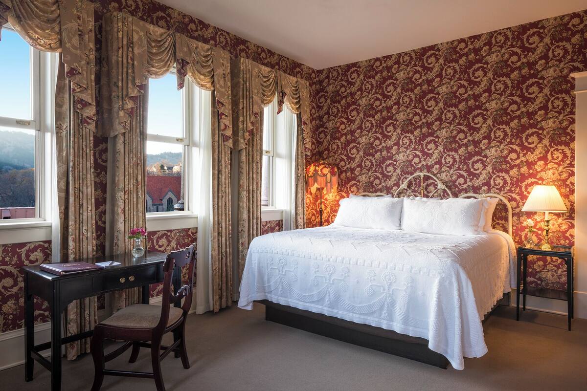 A bedroom with a bed, a desk, and a chair.