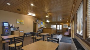 A restaurant with wooden tables and chairs, an ATM, and a sign for breakfast. - Days Inn by Wyndham West Allis/Milwaukee (Milwaukee)