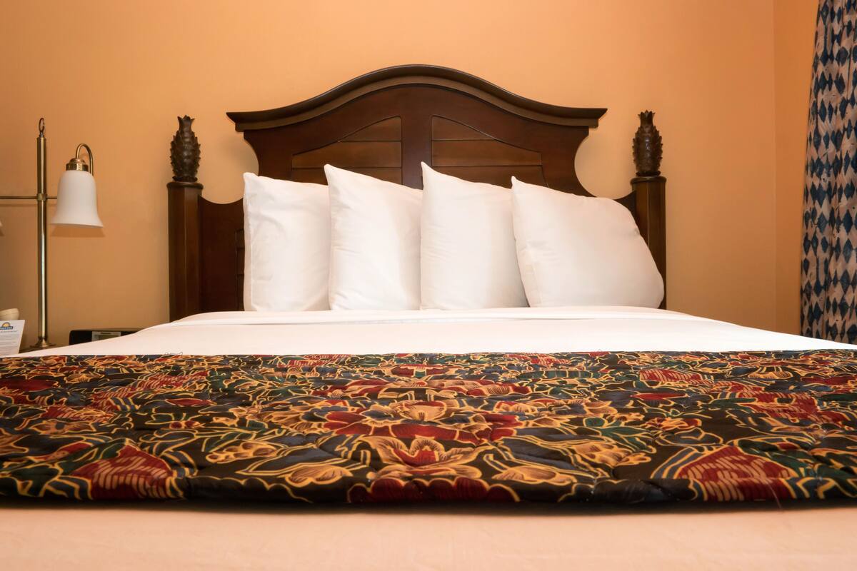 A neatly made bed with white linens and a colorful patterned bedspread.