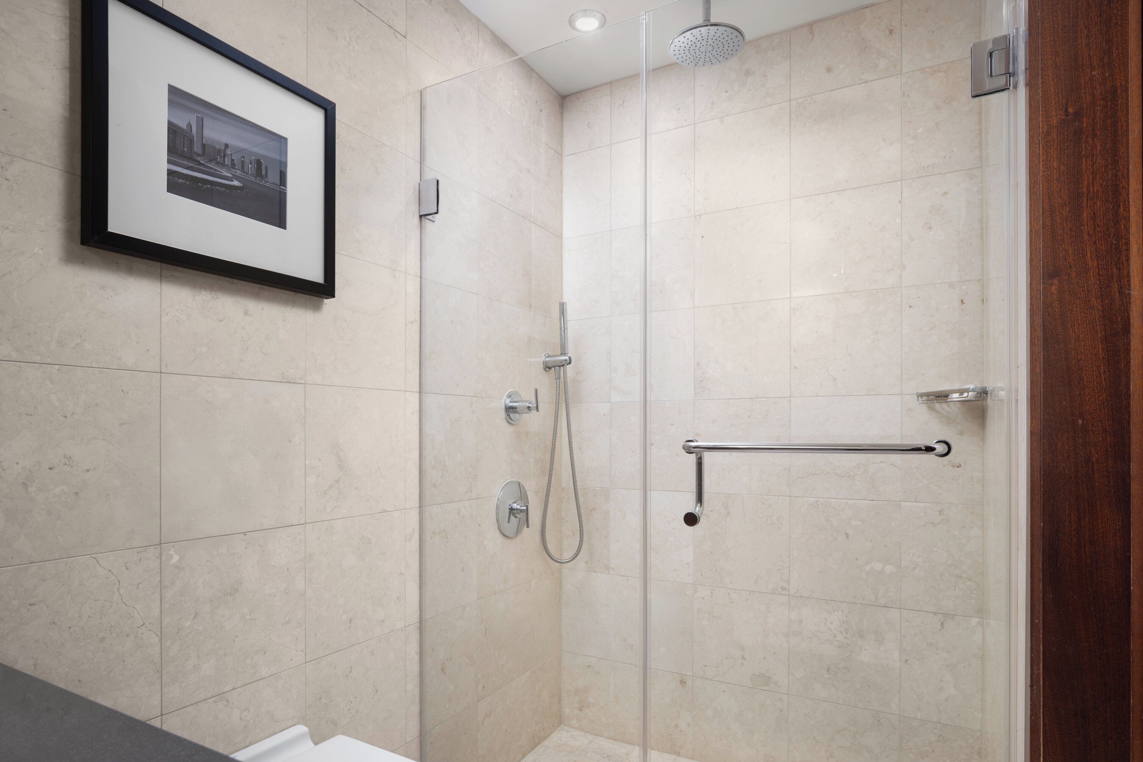 A modern bathroom with a glass-enclosed shower, a framed picture on the wall, and a towel rack.