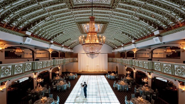 Un salón de baile imponente con un amplio piso para bailar, techo ornamentado y candelabros.