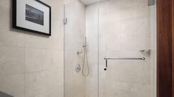 Ein modernes Badezimmer mit einer Duschkabine aus Glas, einem gerahmten Bild an der Wand und einem Handtuchhalter.