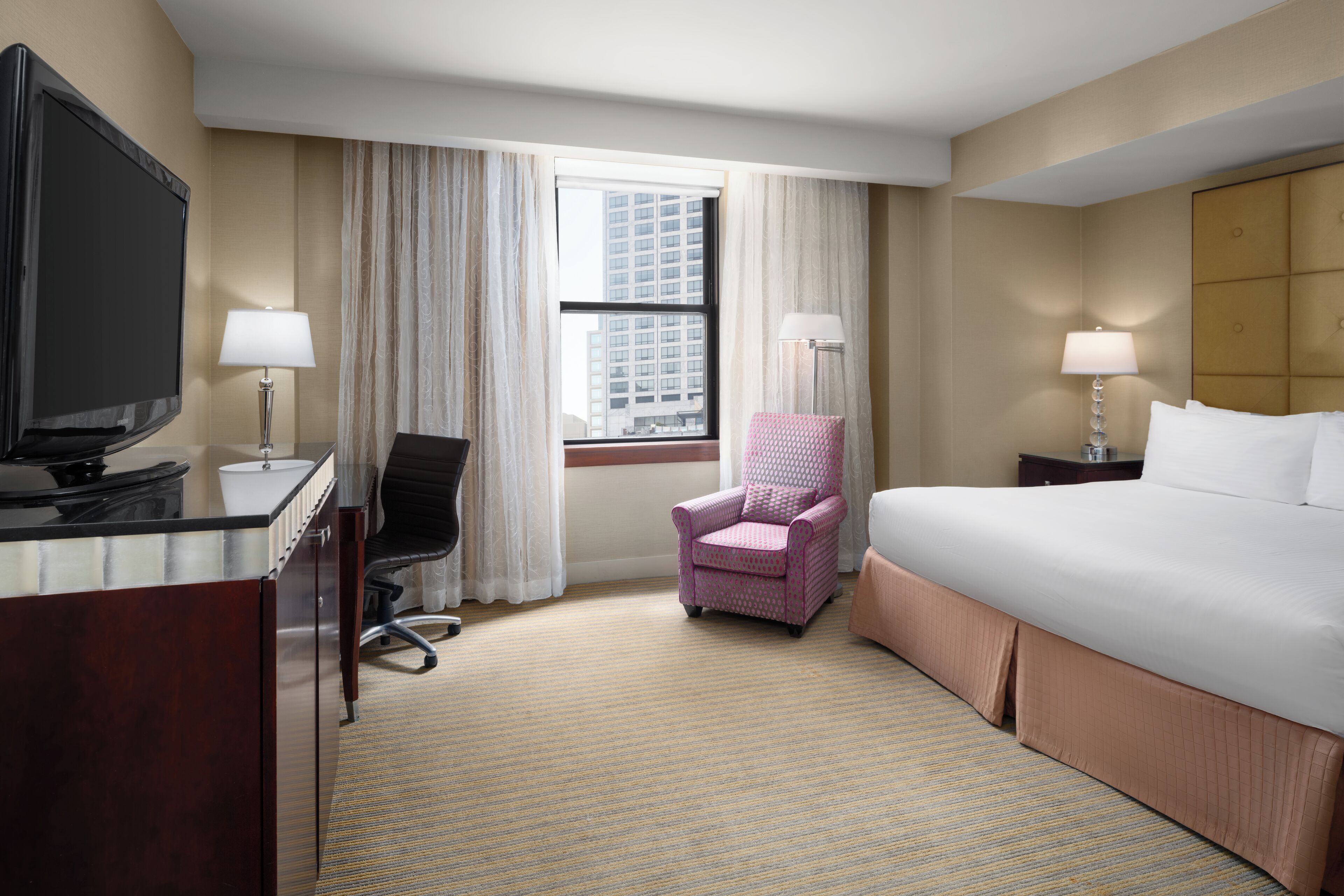 Une chambre d’hôtel équipée d’un lit, d’un bureau, d’une chaise et d’un téléviseur.