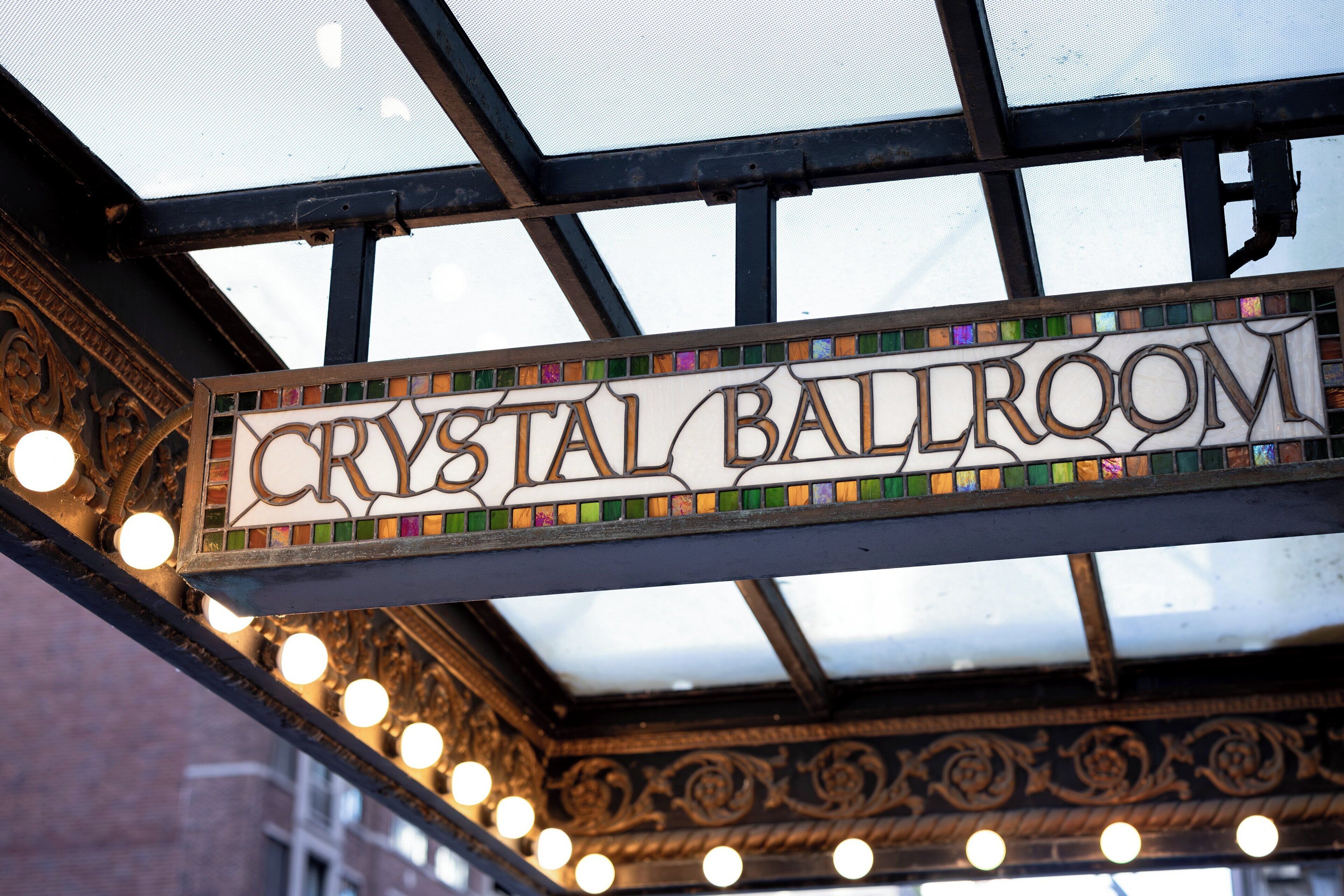Letrero que dice 'Crystal Ballroom' con un borde decorativo y luces colgantes.