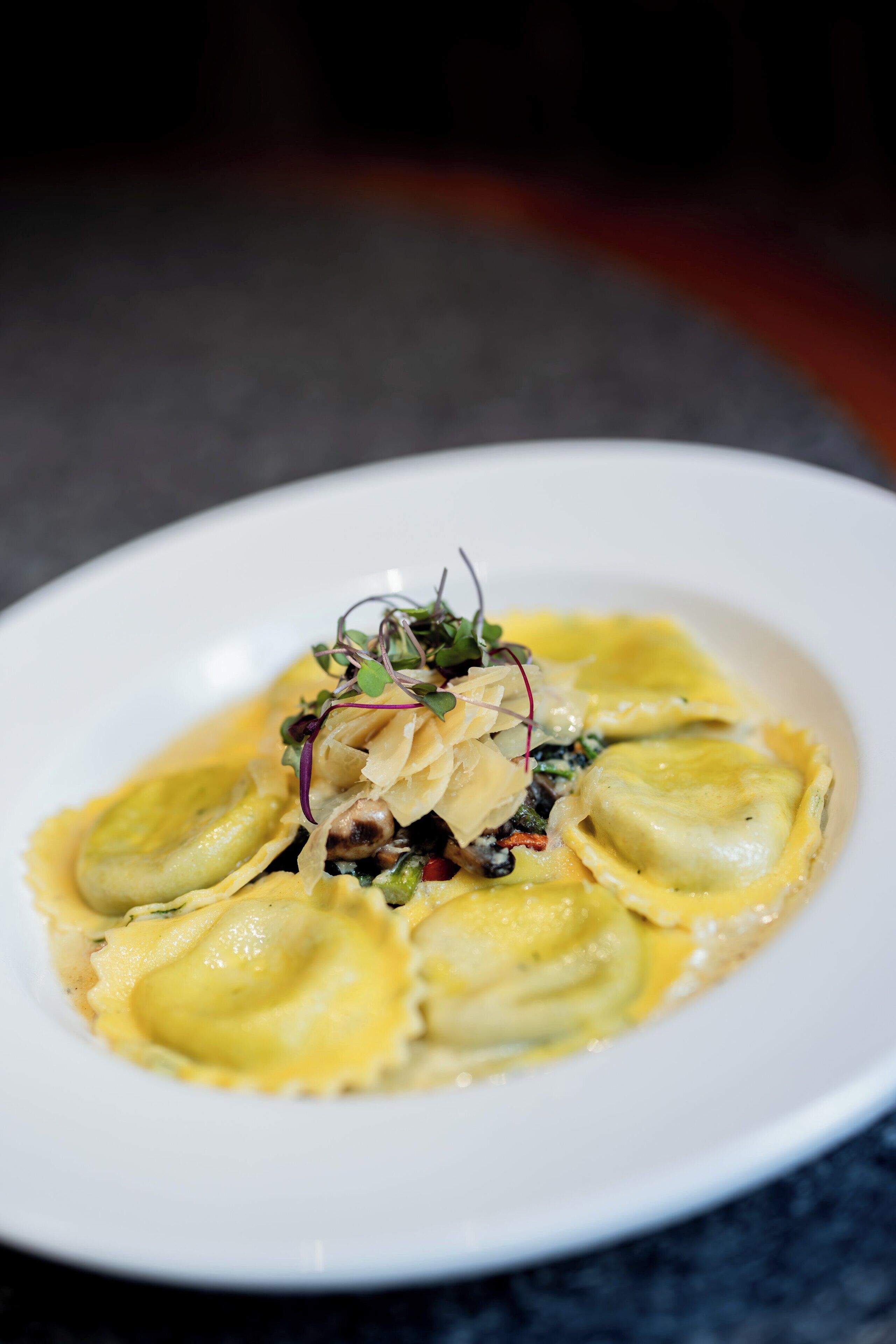 A plate of ravioli with a creamy sauce and garnishes.