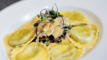 A plate of ravioli with a creamy sauce and garnishes.