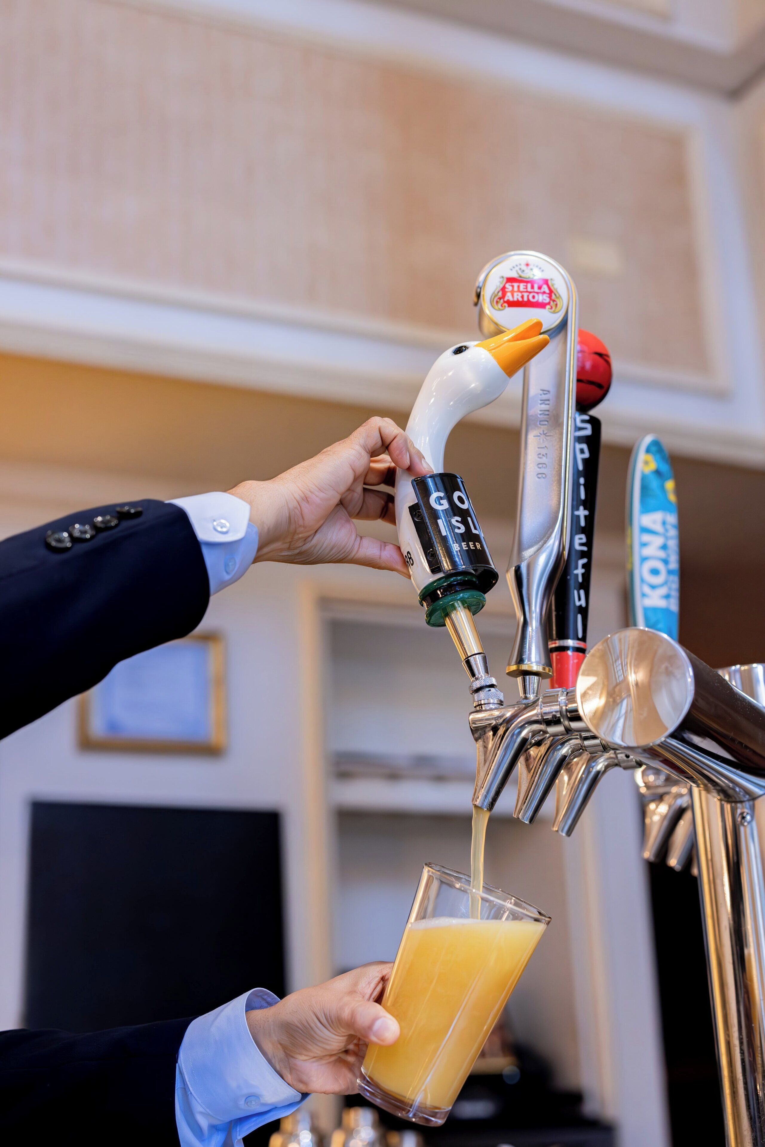 Una mano opera un grifo con la etiqueta 'Stella Artois' para servir una bebida en un vaso.