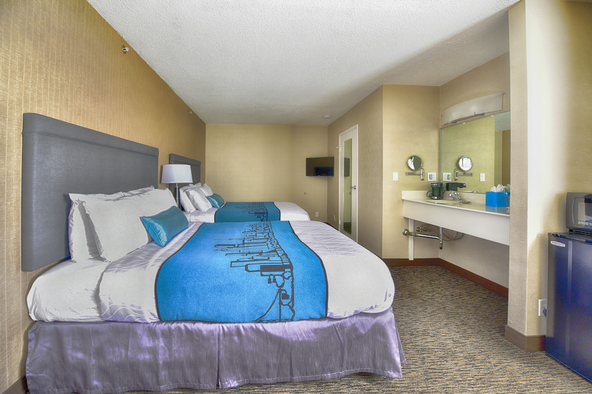 A hotel room with a large bed, a bathroom with a sink and mirror, and a television on a cabinet.
