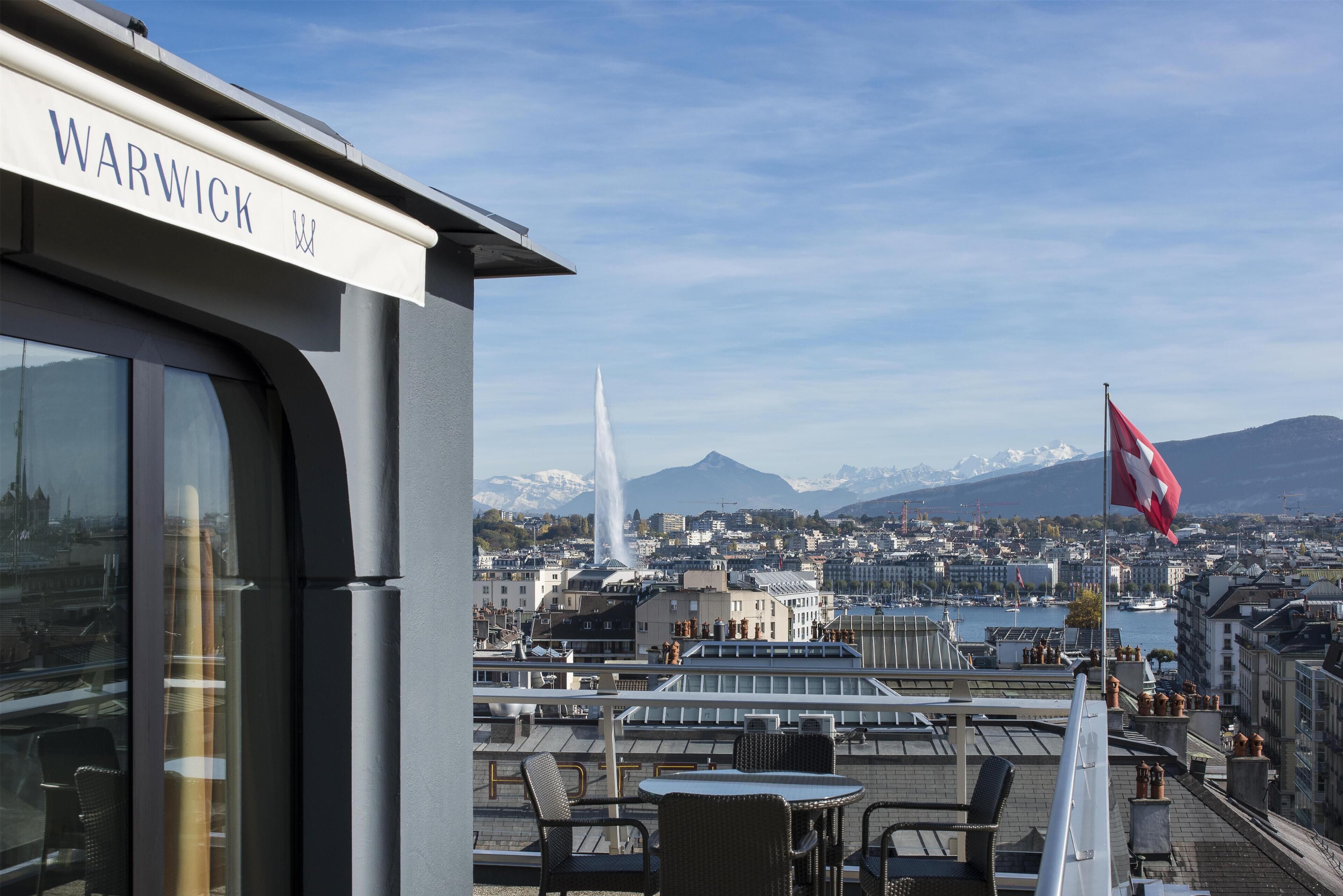 A hotel with a view of a cityscape, including a mountain range and a body of water.