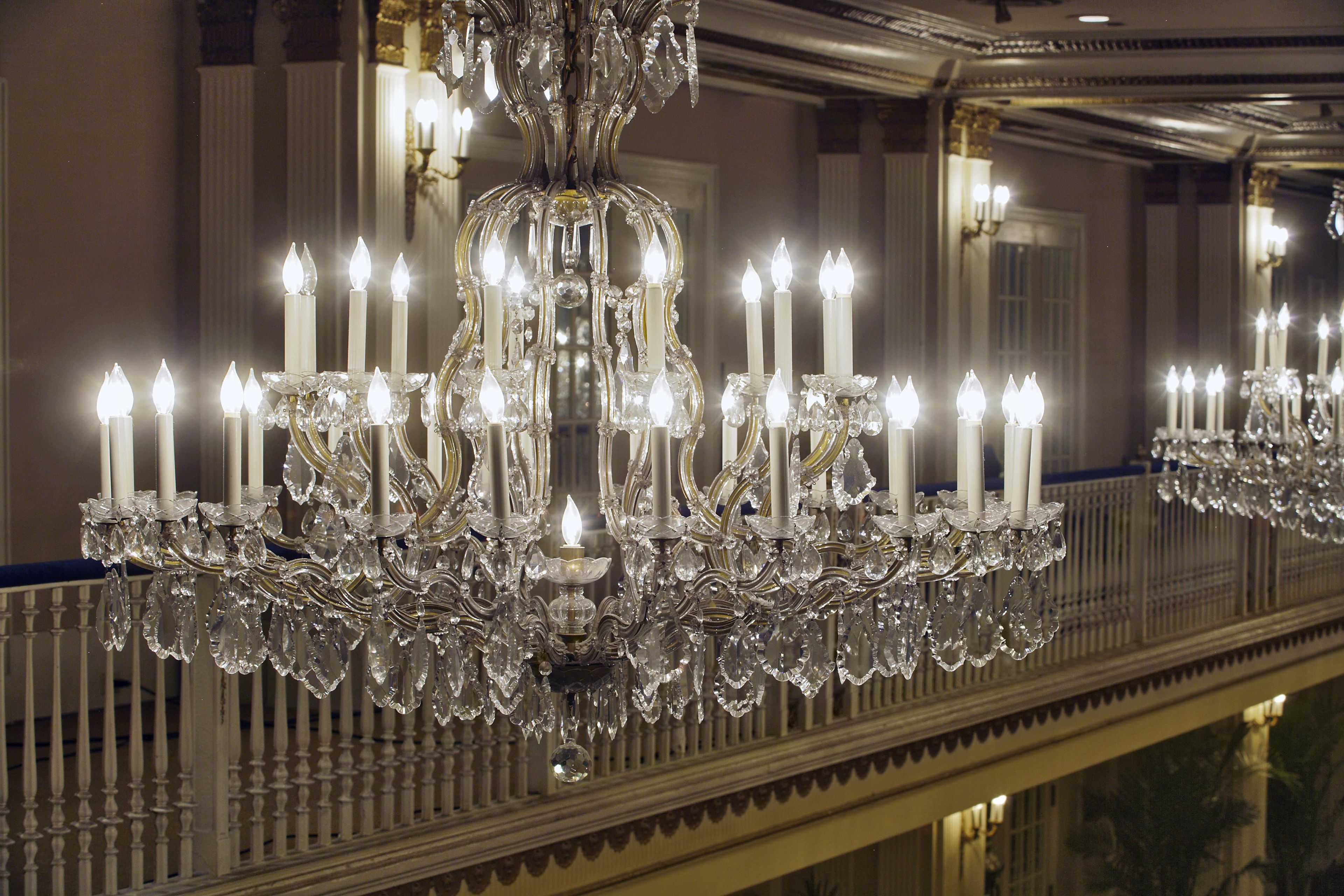 A grand chandelier with multiple candle-like lights and crystal decorations.