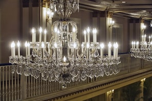 A grand chandelier with multiple candle-like lights and crystal decorations. - The Drake (Chicago)