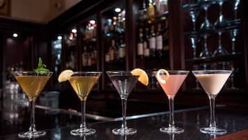 A bar with five martini glasses arranged on a counter, each with a different cocktail and garnish.