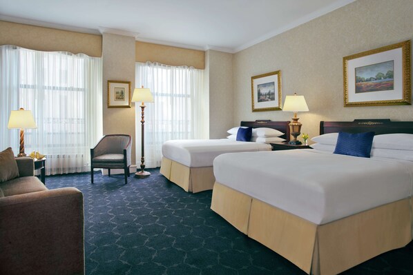 A hotel room with two beds, a sofa, a chair, and two lamps. - The Drake (Chicago)