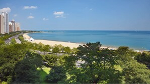 A coastal cityscape with a beach, high-rise buildings, and lush greenery. - The Drake (Chicago)