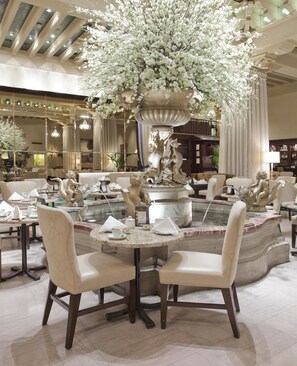 A spacious lobby with a central fountain, multiple seating areas, and a high ceiling with natural light.