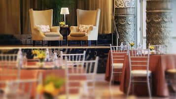 Un comedor elegante con dos sillones, una mesa con un florero y un papel tapiz decorado.