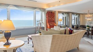 A spacious living room with a view of the ocean, a chandelier, and a traditional red cabinet. - The Drake (Chicago)