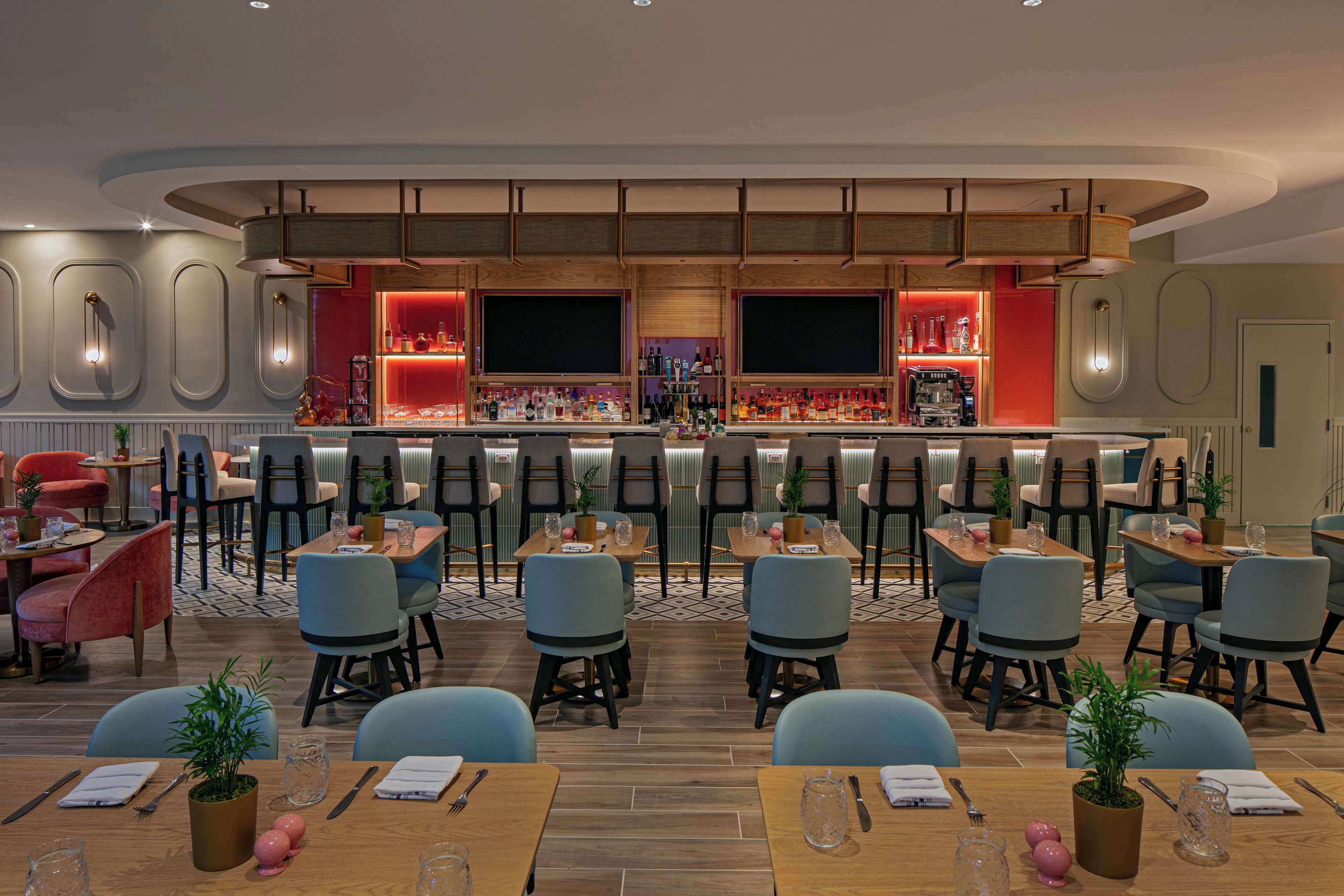 A modern restaurant with a bar area, multiple seating options, and a variety of table settings.