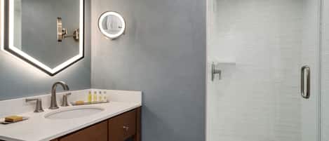 Une salle de bain avec un grand miroir, un lavabo et une douche.