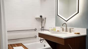 A modern bathroom with a white bathtub, a wooden bench, a vanity with a mirror, and a shower area.