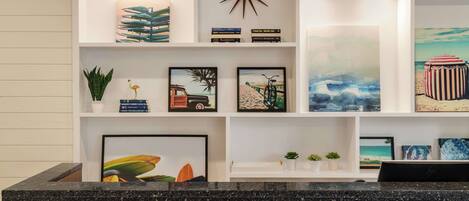 A hotel reception area with a black granite counter, a clock, and various framed artworks on the walls.