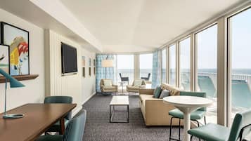 Een moderne hotelkamer met een groot balkon, een zithoek, een eettafel en een televisie.