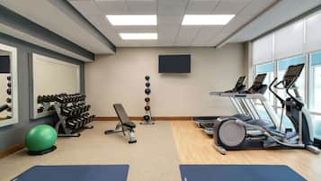 A gym with treadmills, a bench, dumbbells, and exercise balls.