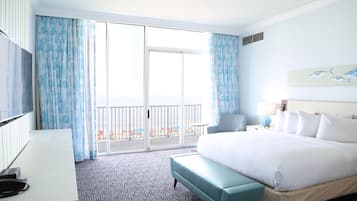 A hotel room with a large bed, a desk with a telephone, a chair, a lamp, and a painting on the wall.