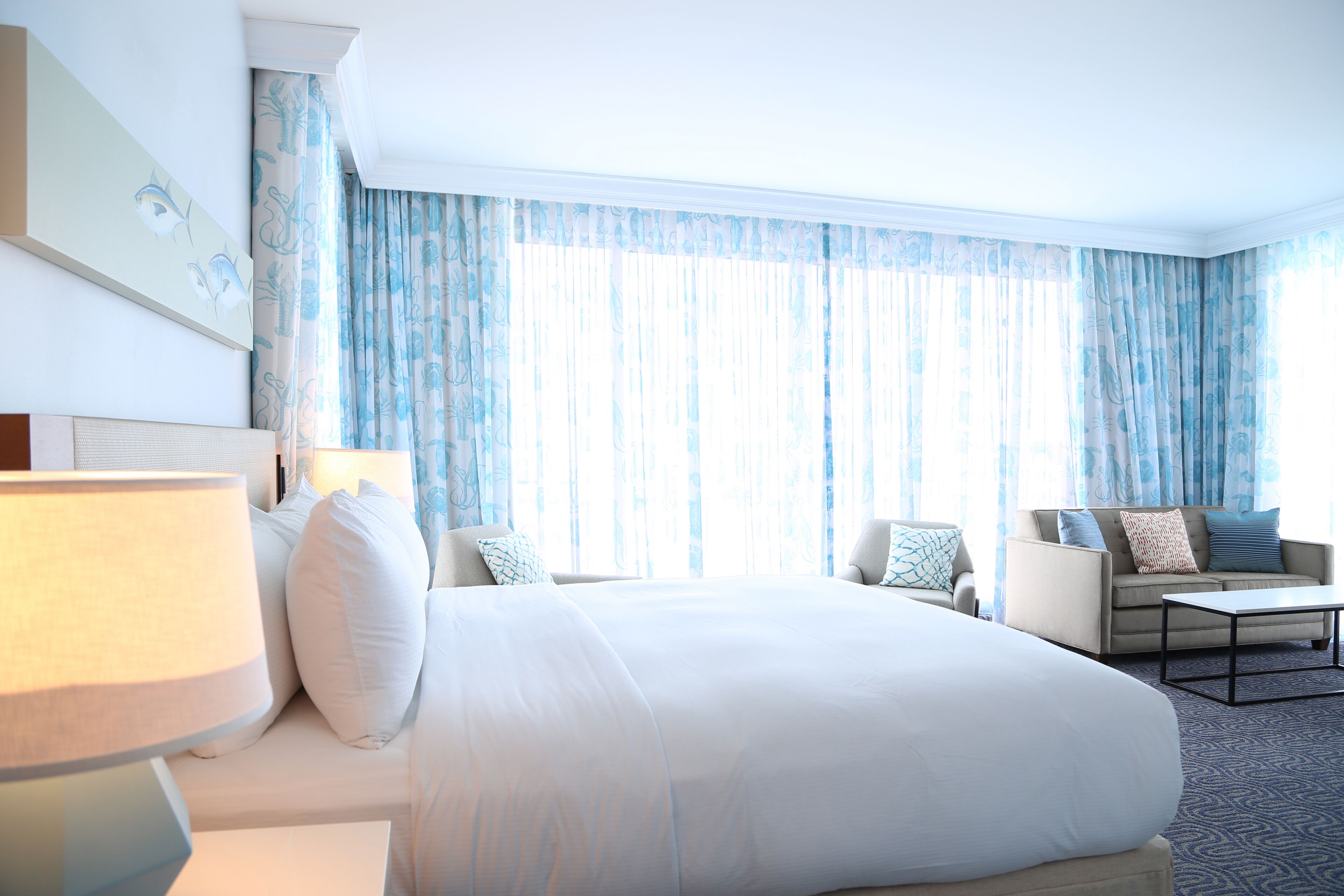 A hotel room with a large bed, a sofa, a coffee table, and a lamp.