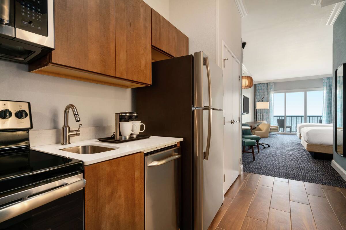 A modern kitchen with stainless steel appliances, wooden cabinets, and a built-in dishwasher.