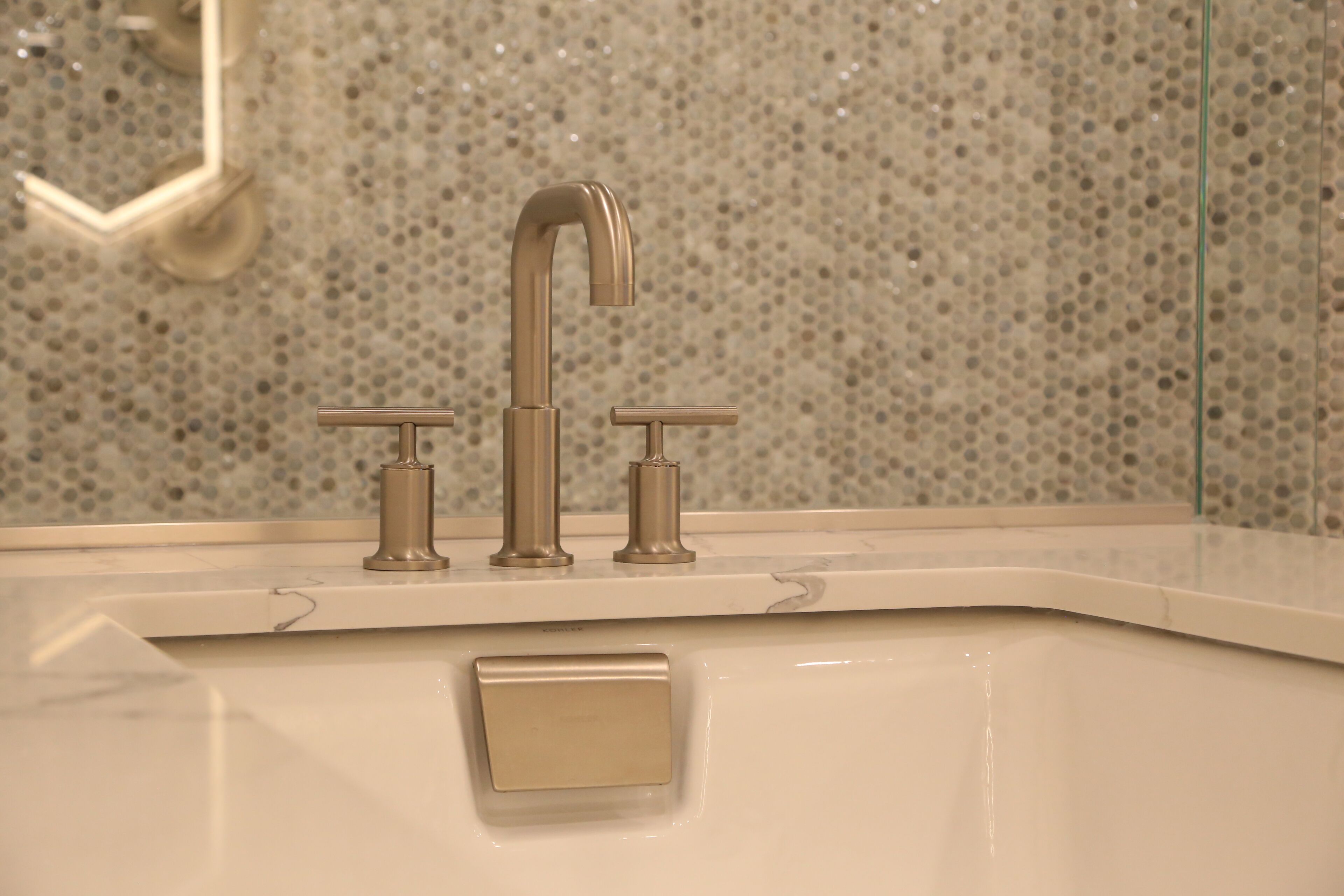 A bathroom sink with a modern faucet and a marble backsplash.