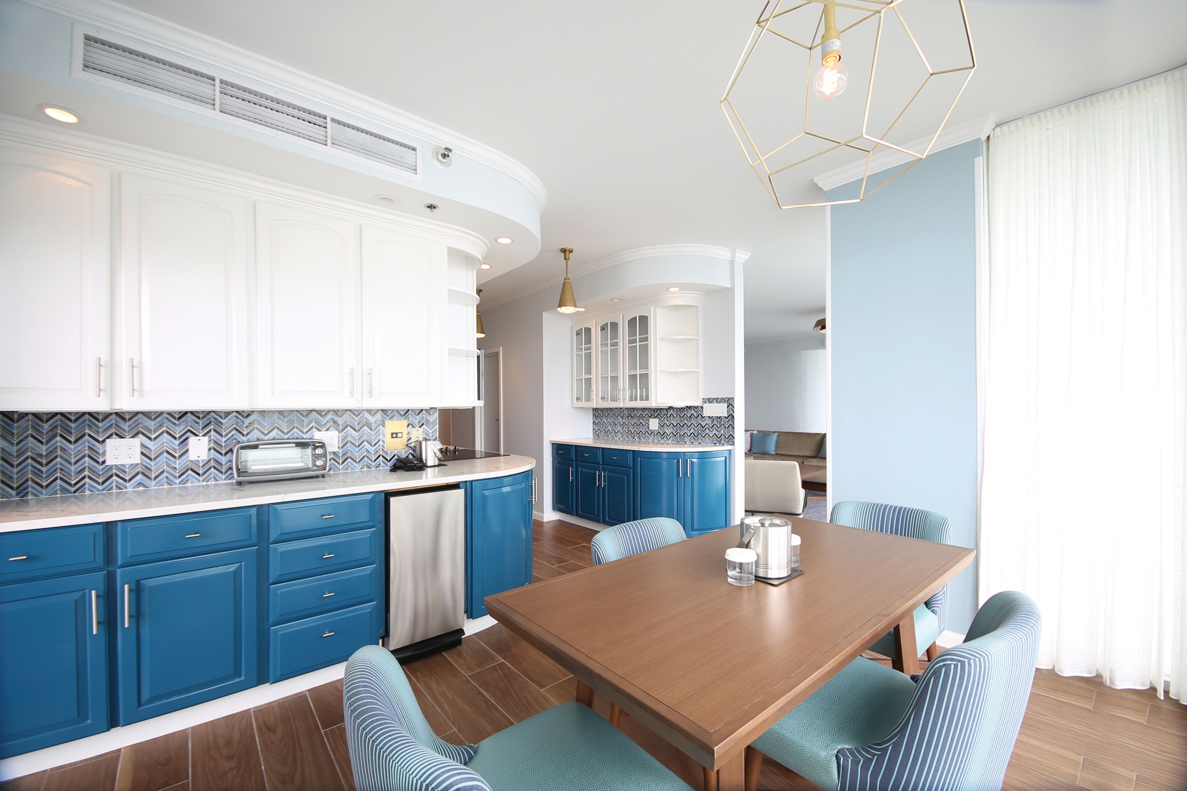 Una cocina moderna con armarios azules, una mesa de comedor de madera y un horno empotrado.