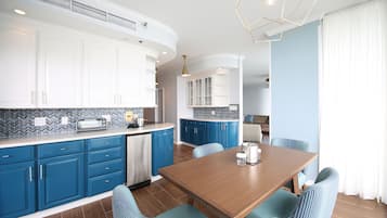Una cocina moderna con armarios azules, una mesa de comedor de madera y un horno empotrado.
