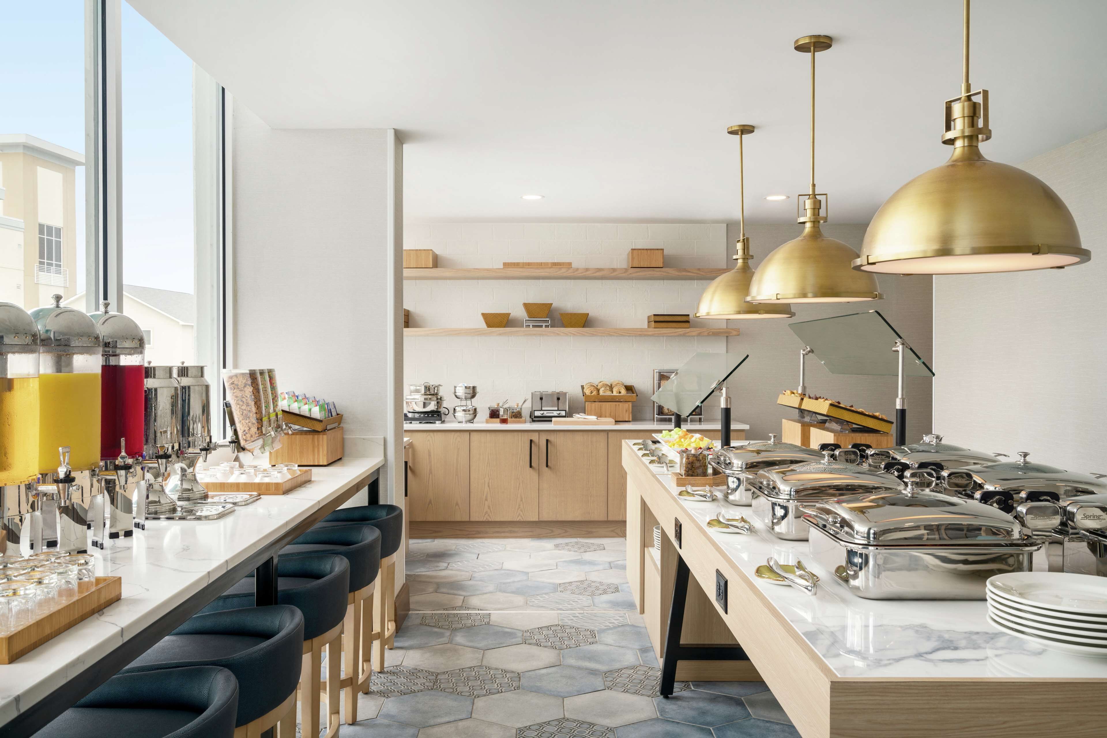 Una cocina moderna con una barra larga, varias estaciones de servicio e iluminación colgante.
