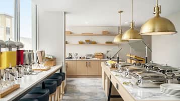 Una cocina moderna con una barra larga, varias estaciones de servicio e iluminación colgante.