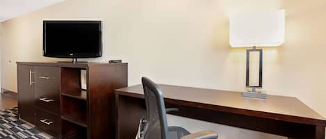 Una habitación de hotel con escritorio, silla, televisión y lámpara.