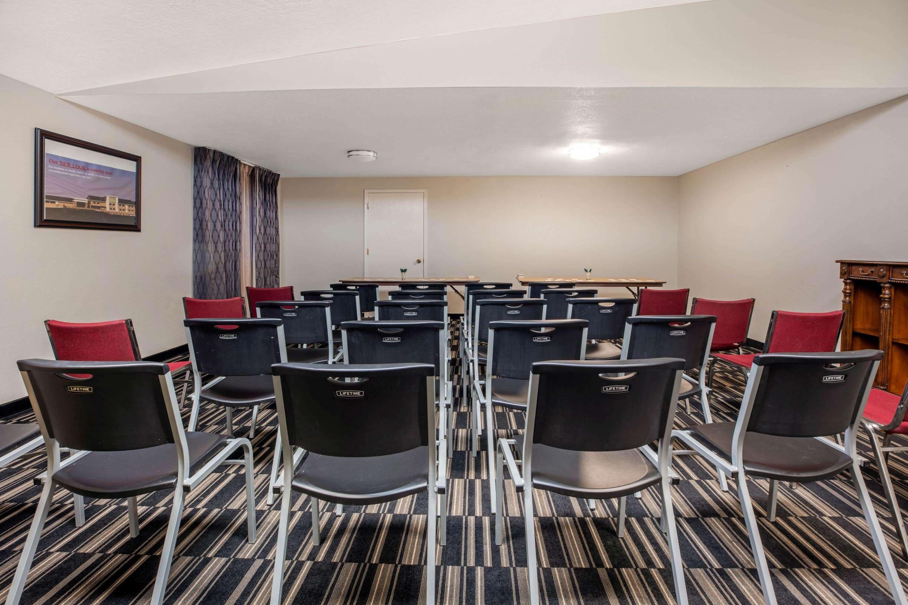 Una sala conferenze con file di sedie, una lavagna e una porta.