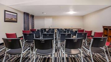 Una sala conferenze con file di sedie, una lavagna e una porta.